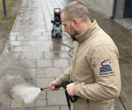 Meister peseb betoonplaatidest kõnniteed, parkla pesualal tähistatakse töötsoon enne alustamist koonustega.