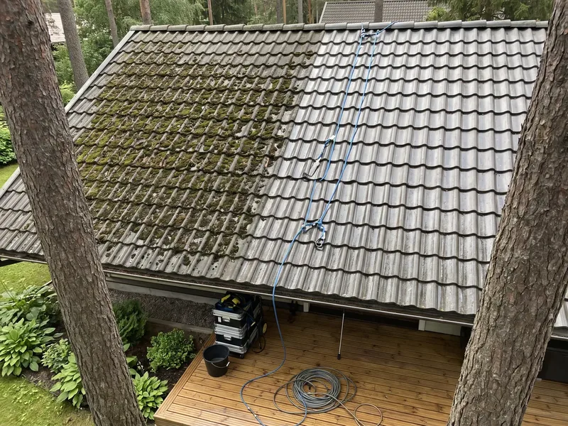 Männikrundi maja betoonkivikatus ülalt, vasak pool on veel samblane ja parem pool pestud, all terrassil seisavad pesur ja kokkukeritud voolik, katusele minnakse alles pärast hommikukaste kuivamist, sest märg samblane kivi on libe.