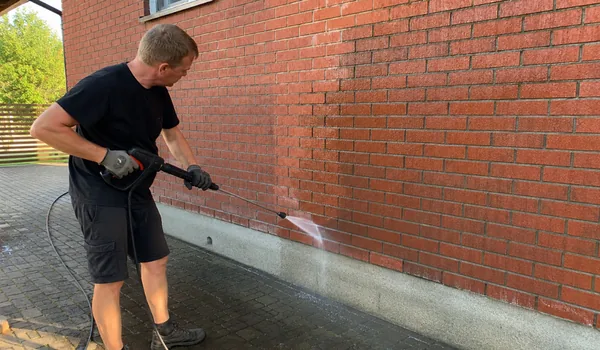 Tellisfassaadi pesu, meister peseb survepesuriga punase tellisseina alumist osa, tellissein tehakse enne pesuvahendit puhta veega märjaks, et vahend ei imbuks kuiva tellise pooridesse.