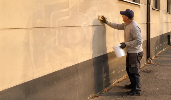 Varigrafiti järeltöötlus käsnaga, krohvil on näha kustutatud grafiti hele kontuur, värvivari paistab kõige selgemalt madala hommikupäikesega.